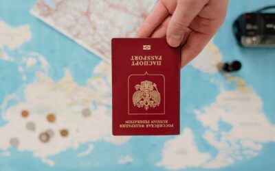 A hand holding a Russian passport over a map, suggesting travel preparation.