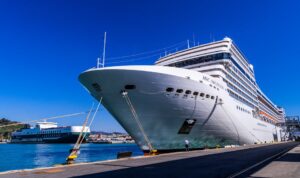 A large cruise ship docked at Barcelona port under a clear blue sky, showcasing maritime travel.
