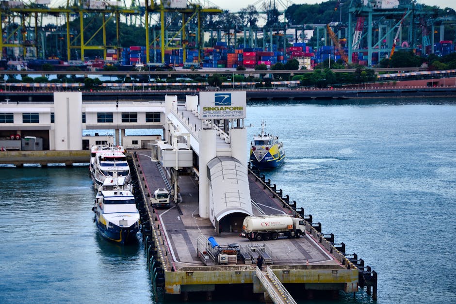 Boats docked at Singapore Harbourfront Center with industrial port backdrop, highlighting urban waterfront.