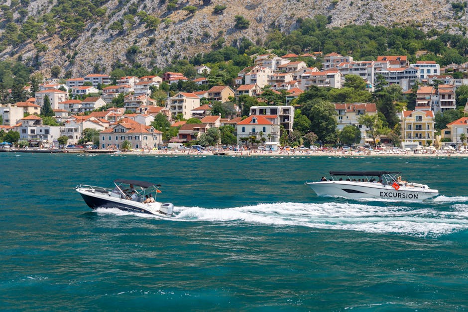 Two boats cruising along the Adriatic coast with a scenic coastal town backdrop.