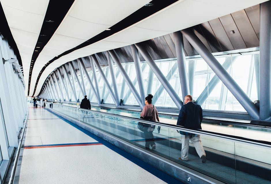 Travelers walking through a bright modern airport corridor with glass walls.