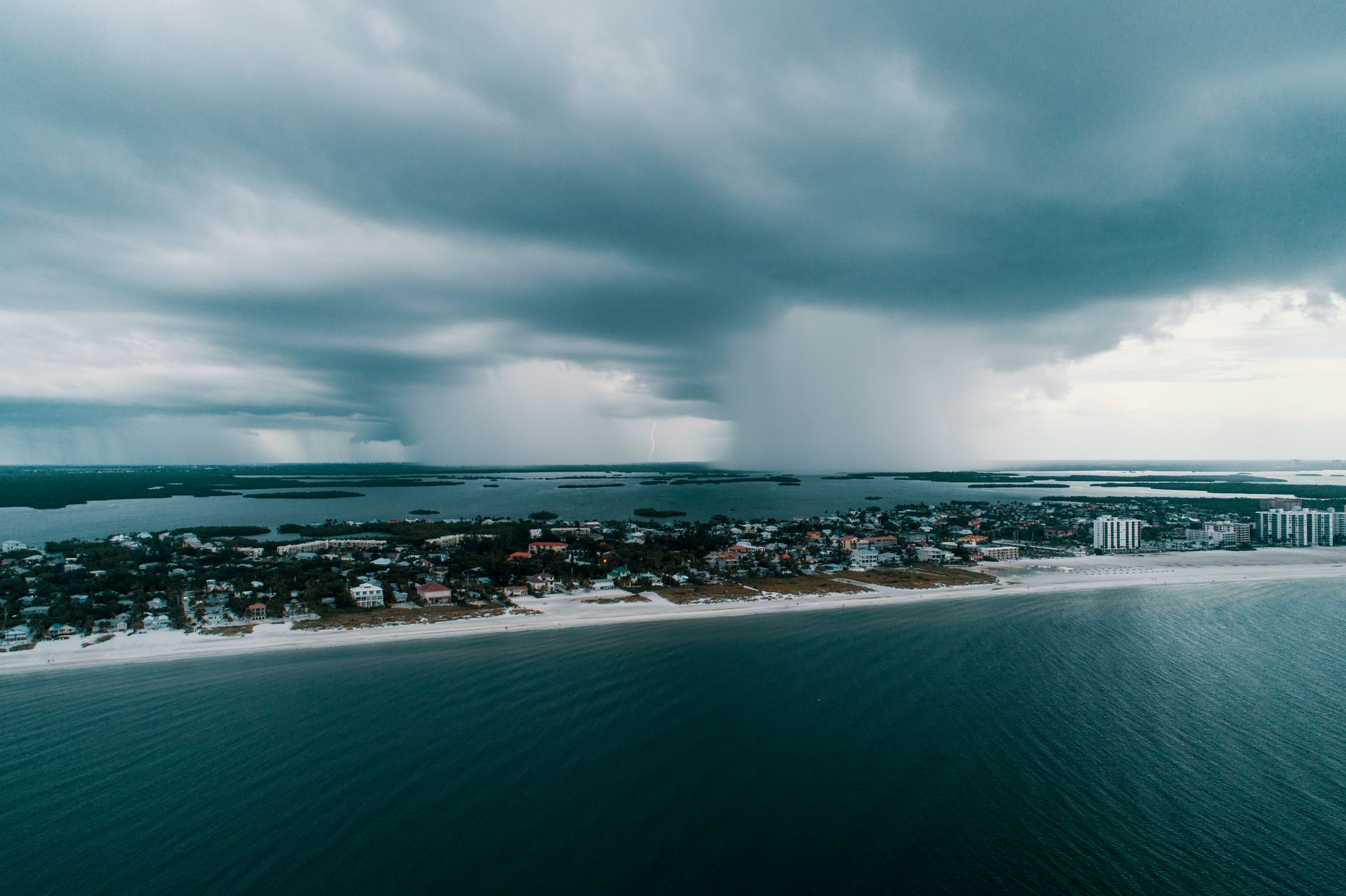 Aerial view of a tropical storm approaching a coastal village during US hurricane season