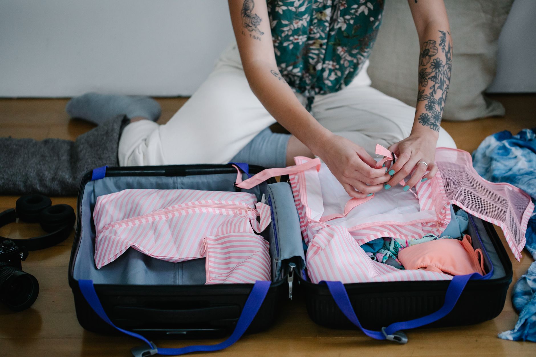 Woman packing a travel suitcase on the floor while preparing clothes for a US trip