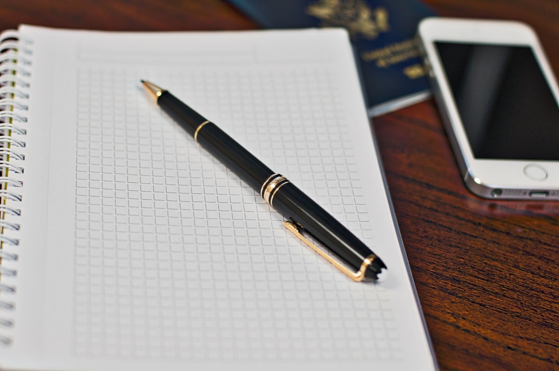Passport, smartphone and notebook on a desk while preparing travel documents for the USA