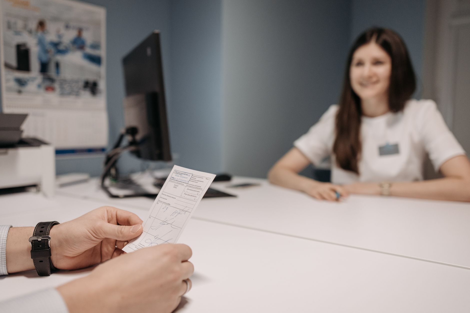 An applicant handing documents across a desk at a visa interview