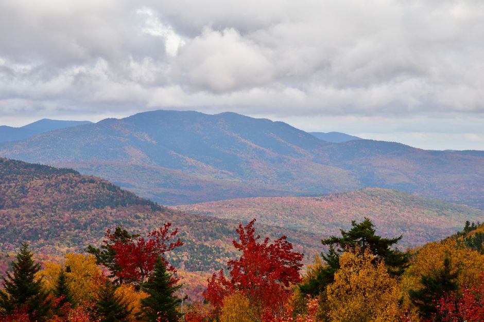 New England fall foliage covering forested mountains in peak autumn color for a 2026 road trip